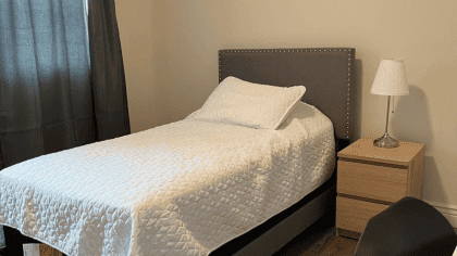 Quarto privativo com cama de solteiro e banheiro privativo